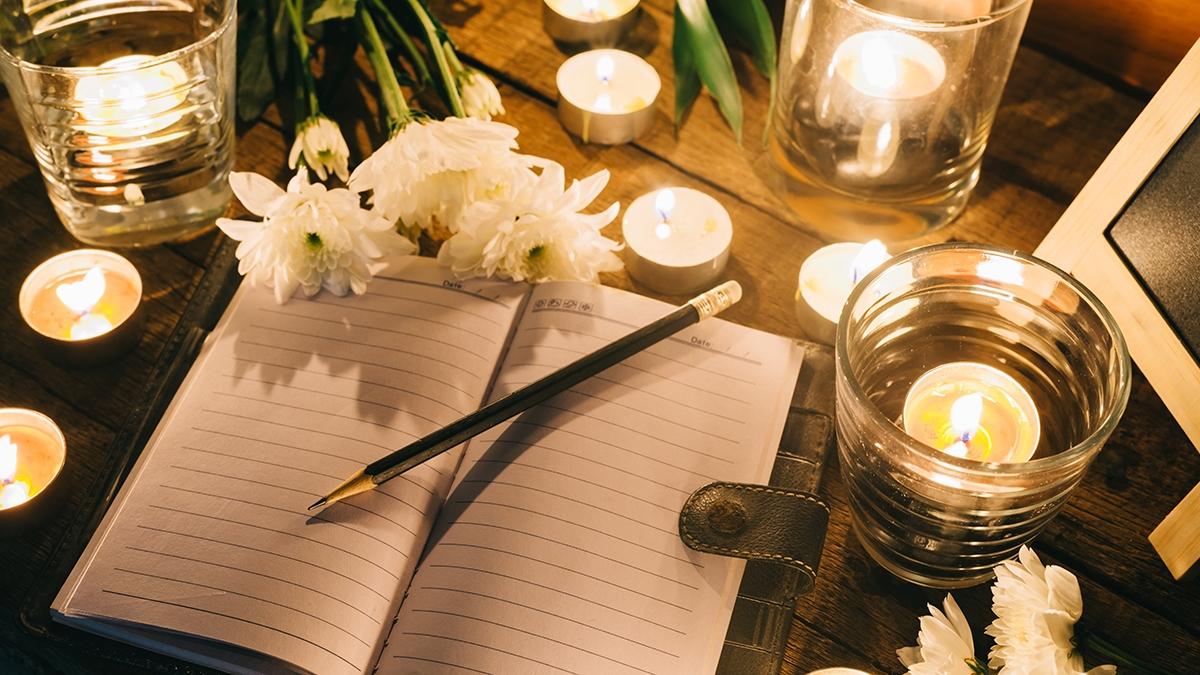 Writing in memory, pencil on empty notebook among candles