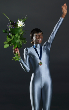 Woman athlete on victory podium with flowers and arm raised. Gold Medal Olympian with Olympic Bouquet