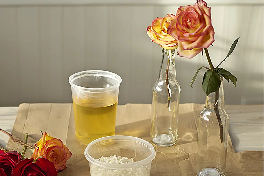 a photo of wax flowers with a wax rose cooling upright in a bottle