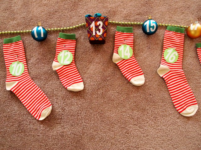 diy advent calendar with Christmas Ornaments and Socks Strung up on Garland