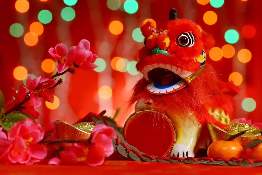 Chinese new year festival decorations, miniature dancing lion and ancient money on red glitter background.
