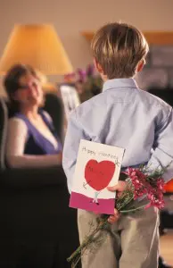 Boy giving hand-made card and flowers to mom