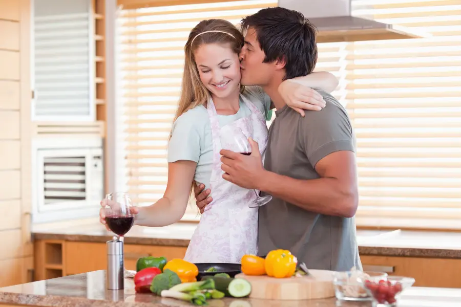Valentines date ideas with a man and woman cooking in a kitchen and drinking wine.