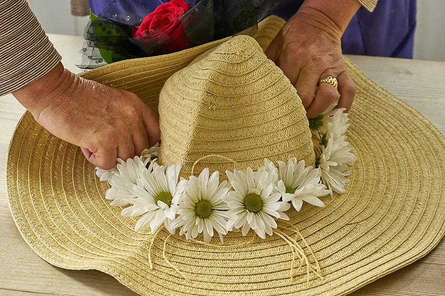 Glue flowers onto brim of hat