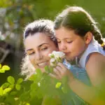 A photo of best smelling flowers with a girl smelling a white rose