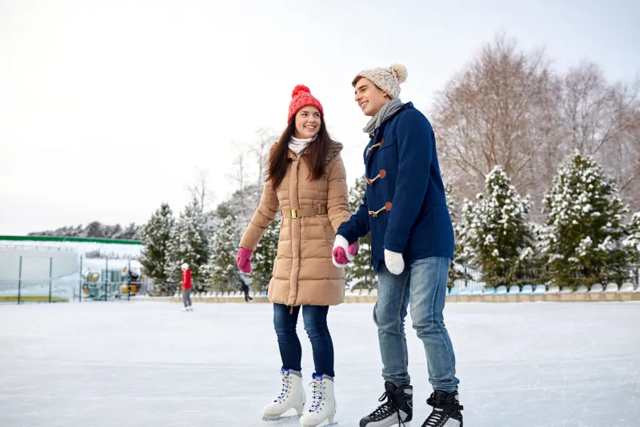 holiday city guide couple holding hands ice-skating outdoors