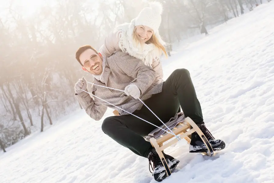Couple Sledding in Winter Snow