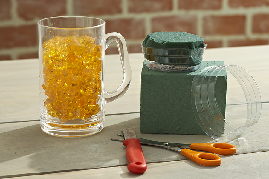 Beer mug full of acrylic gems next to flower crafting items.