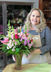 Florist Develyn Reed posing with floral arrangement 