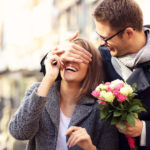 Young man surprising woman with flowers