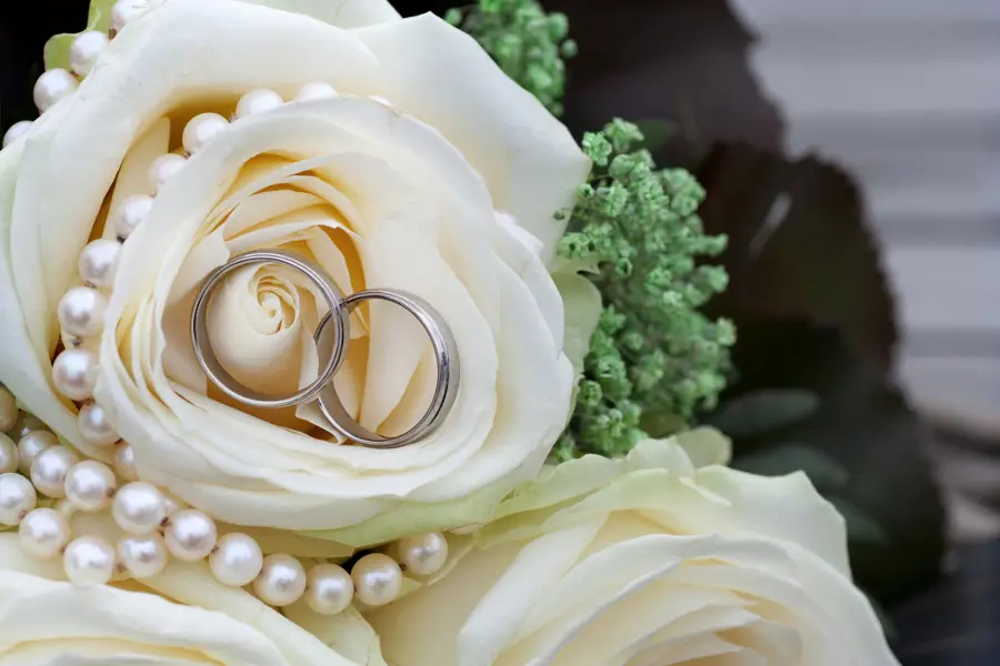 anniversary date ideas with wedding rings presented in a bouquet of white roses