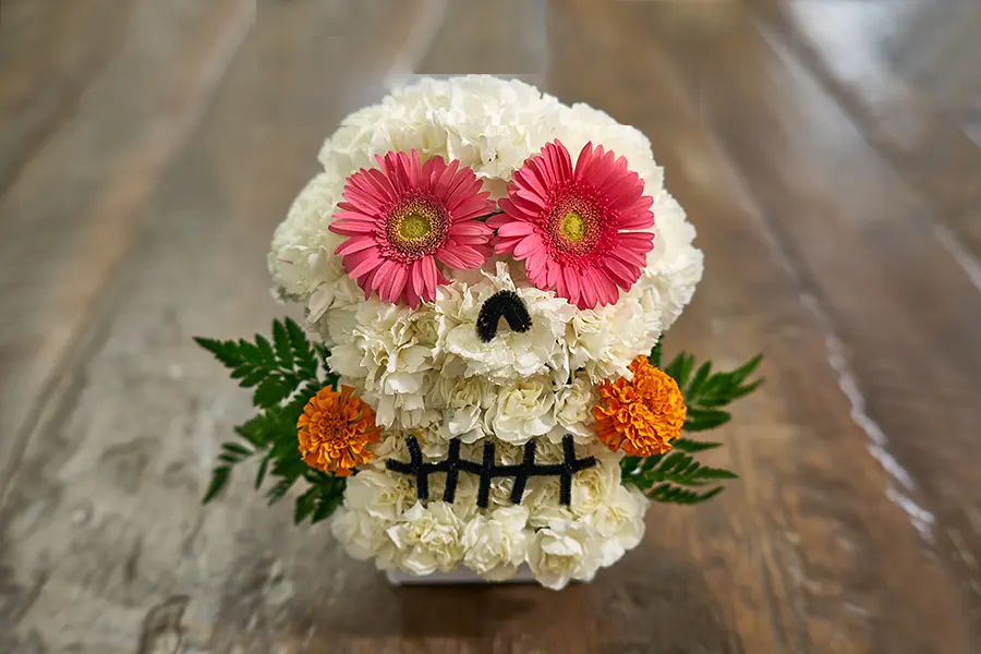 white flower skull with pink flower eyes with marigold flowers