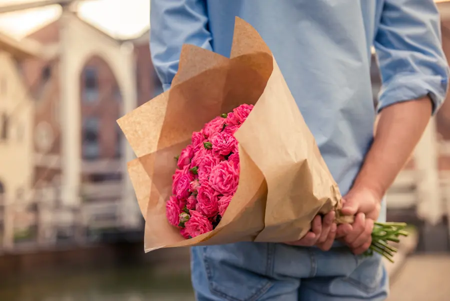 fresh flowers with person holding flowers behind back