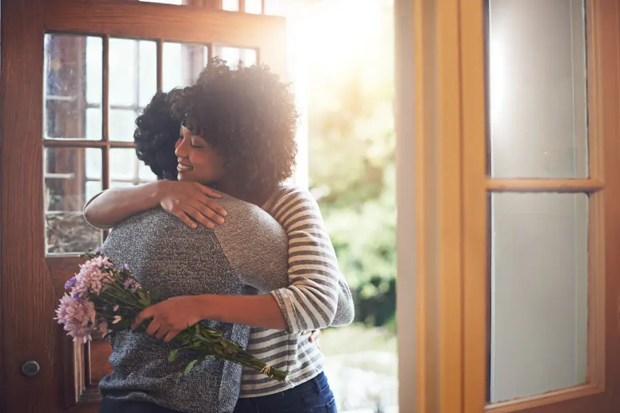 fresh flowers with woman giving a hug holding flowers in doorway