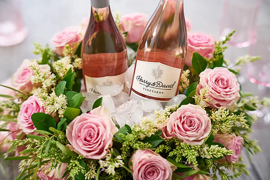 a photo of a roses and rosé wreath with bottles of wine in the wreath