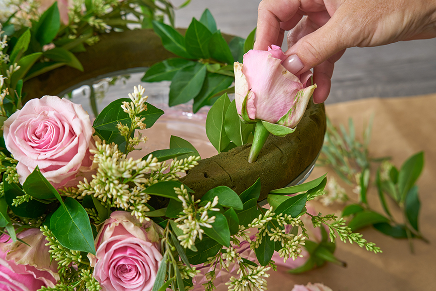 a photo of a roses and rosé wreath with covering wreath base with flowers