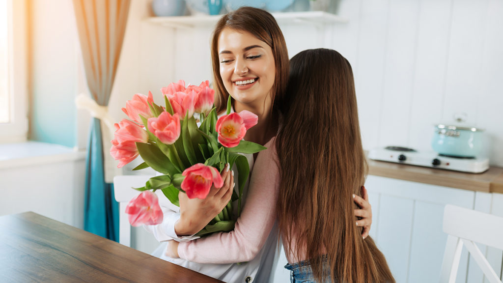 una foto de ideas de regalos para el día de la madre: niña regalando flores a mamá