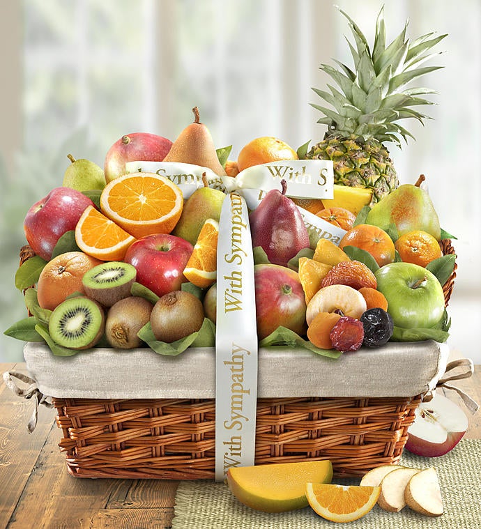 A large basket of fruit with a ribbon wrapped around it that says "with sympathy".