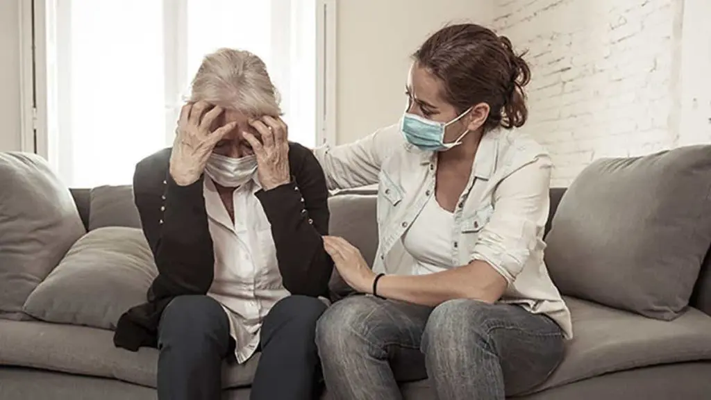 Woman wearing mask comforting older woman