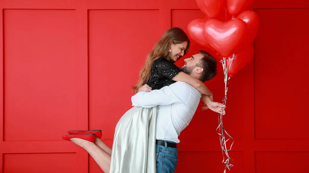 Man holding woman with heart balloons