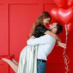 Man holding woman with heart balloons