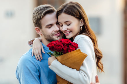 Couple embraces with bouquet of roses