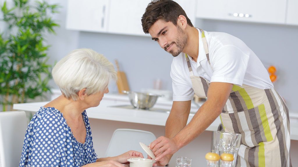 Waiter serving senior woman lunch