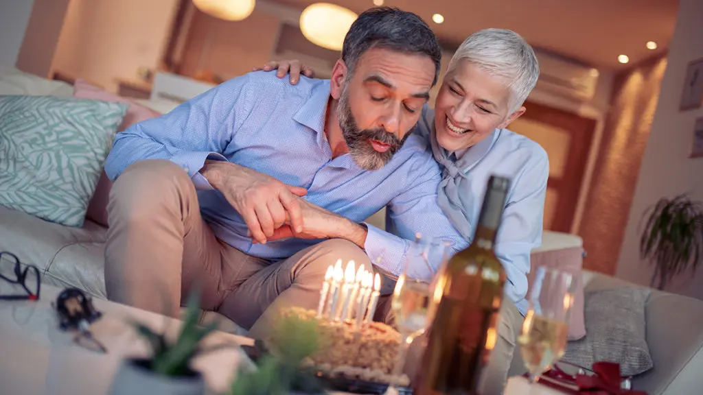 Man blowing out birthday candles on cake