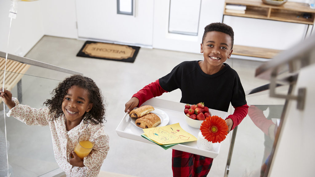 a photo of mother's day: Boy and girl bringing mom breakfast in bed