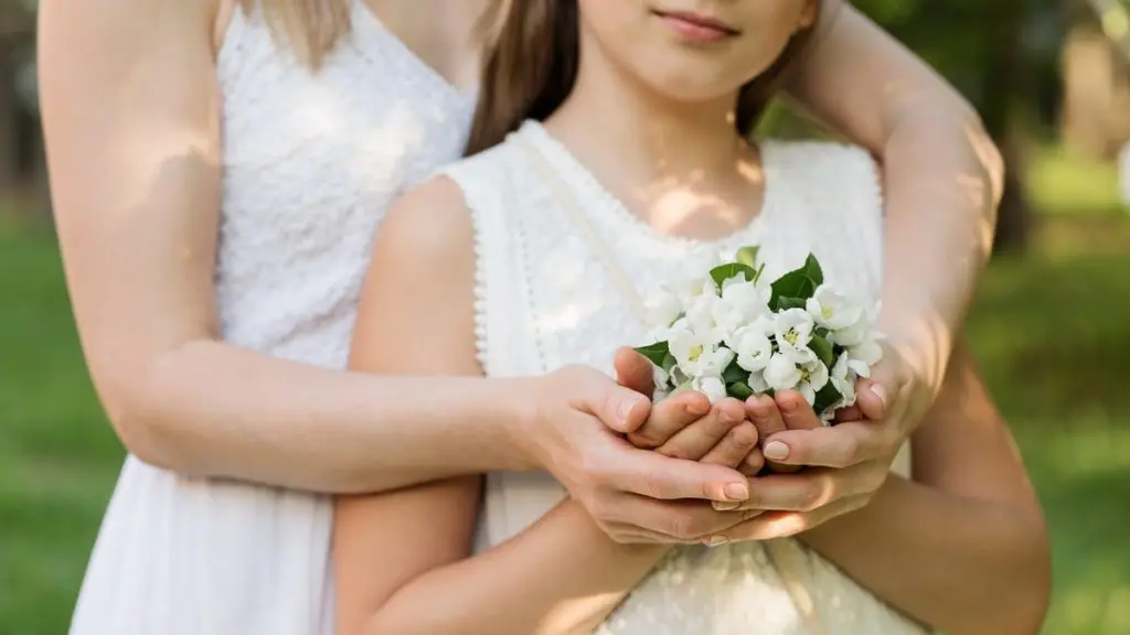 Girl and mom in white dresses with flowers