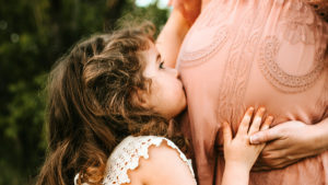 Mommy Brain es la forma natural de ayudar a las madres a adaptarse a la maternidad.  Esta foto muestra a una niña besando el vientre de su madre. 