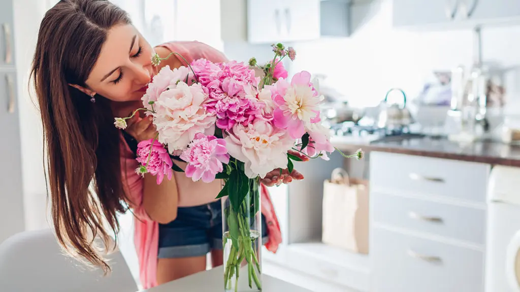 Woman smelling pink peonies