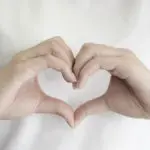 self-compassion with woman making a heart with her hands