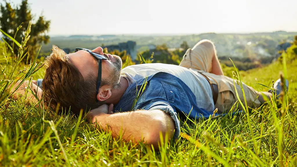 Photo of man lying on grass enjoying peaceful sunny day
