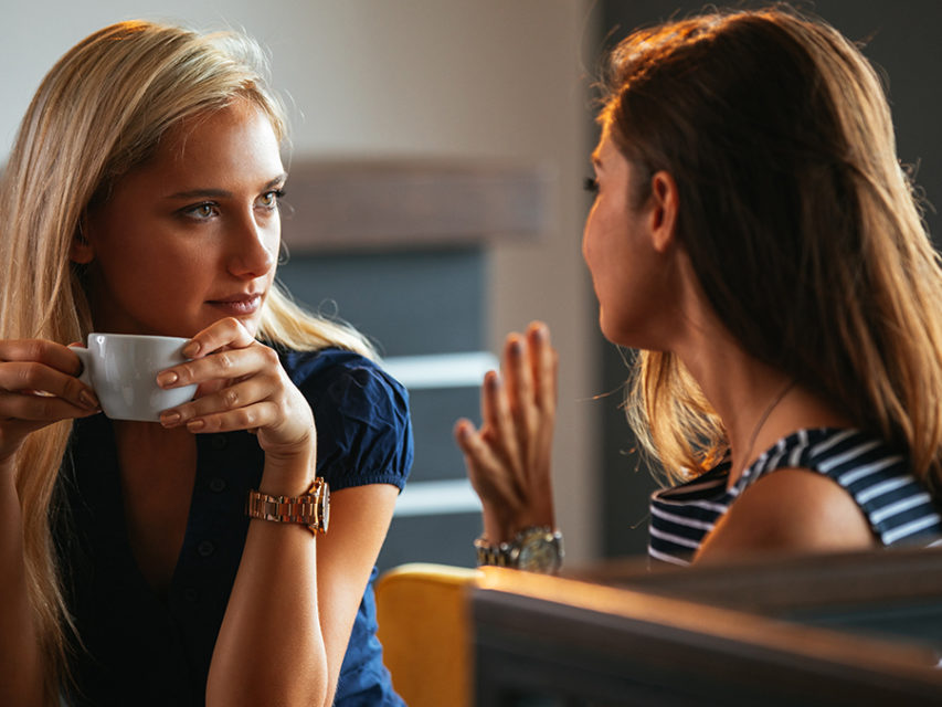 Photo of two women talking while drinking coffee