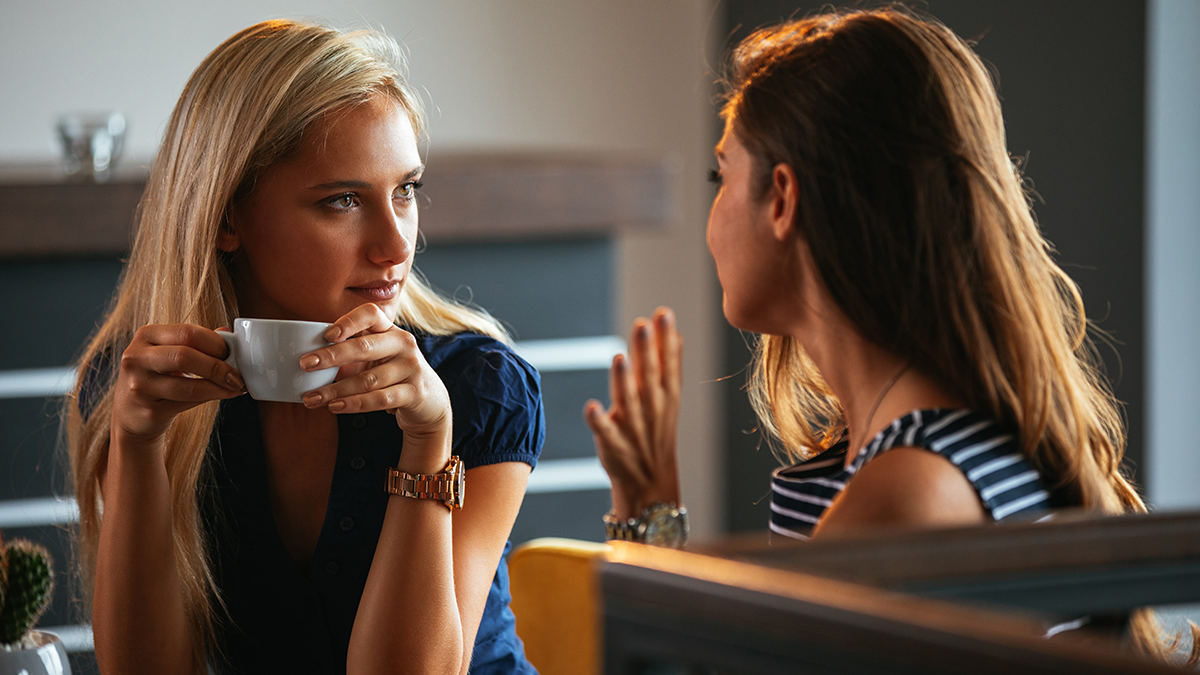 Photo of two women talking while drinking coffee