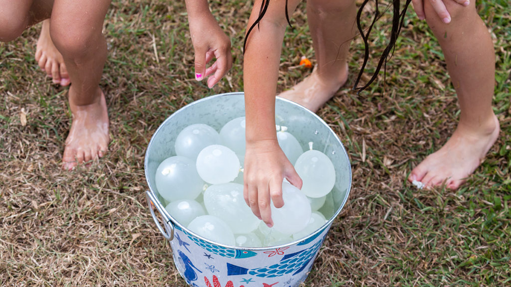 Family reunion games with kids grabbing water balloons from a bucket