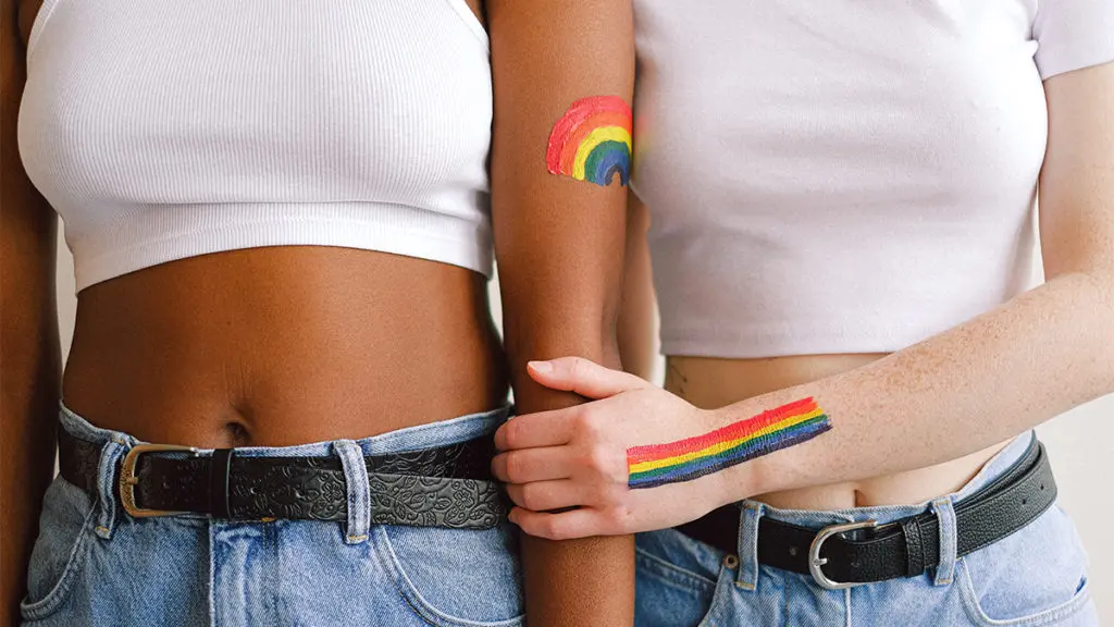 Two women with rainbows painted on their arms