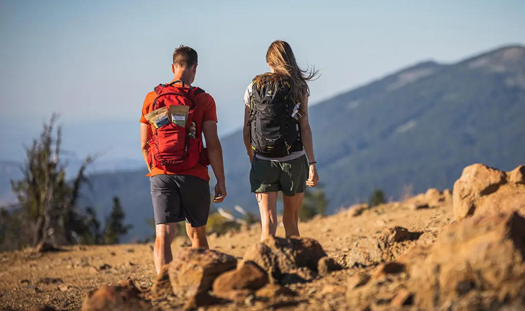 a photo of summer vacation with a couple taking a hike