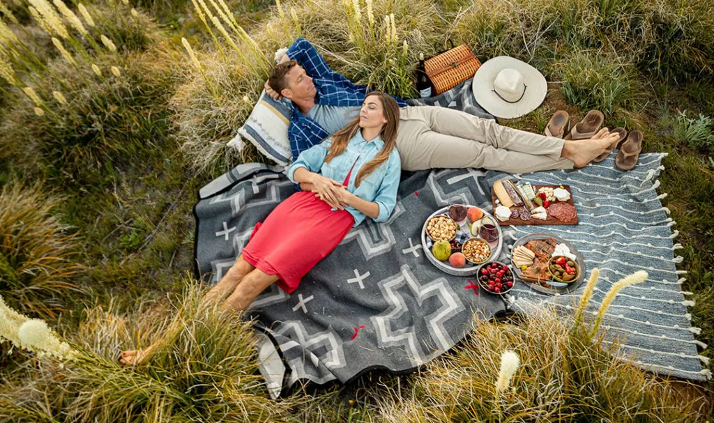 a photo of summer vacation with a couple relaxing at a picnic