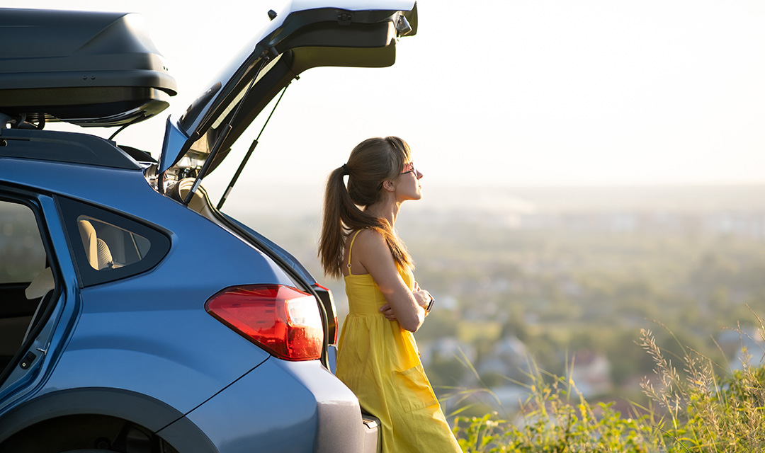 photo of make the most of summer with a woman leaning against her car staring out at the sky