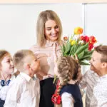 a photo of students giving their teacher flowers