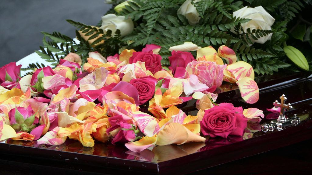Floral arrangements for a funeral should be colorful and joyful. This photo shows yellow and red flowers atop a casket.