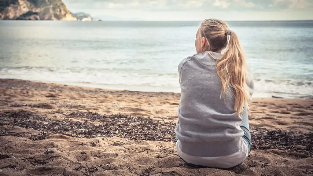 importance of remembrance with young woman remembering a lost loved one while sitting alone at the seashore