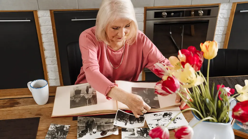 importance of remembrance with elderly woman looking through photos of deceased friends.