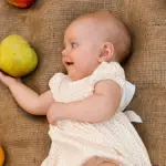 Photo of a baby holding an apple, a popular fruit to celebrate September birthdays.