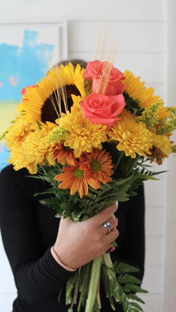 loving fall with person holding bouquet of sunflowers and mums