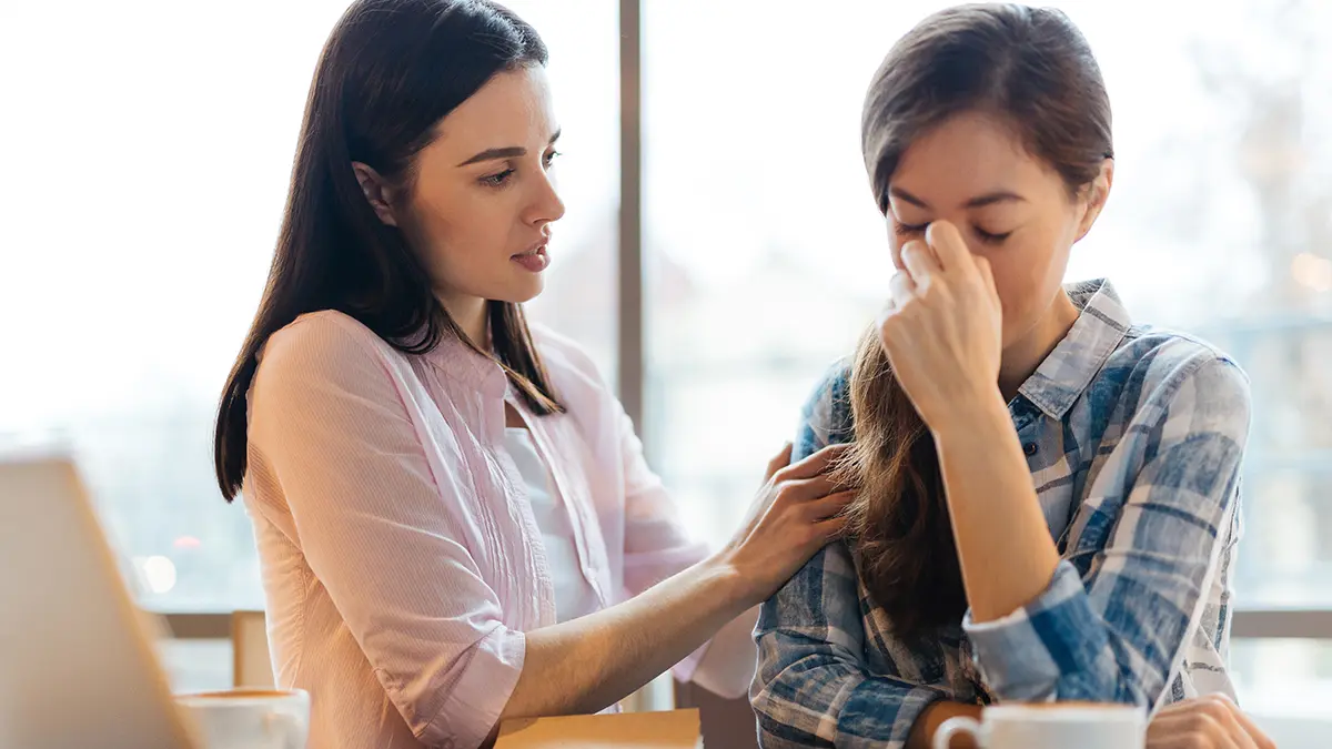 Photo of a woman comforting a friend who has received a terminal illness diagnosis