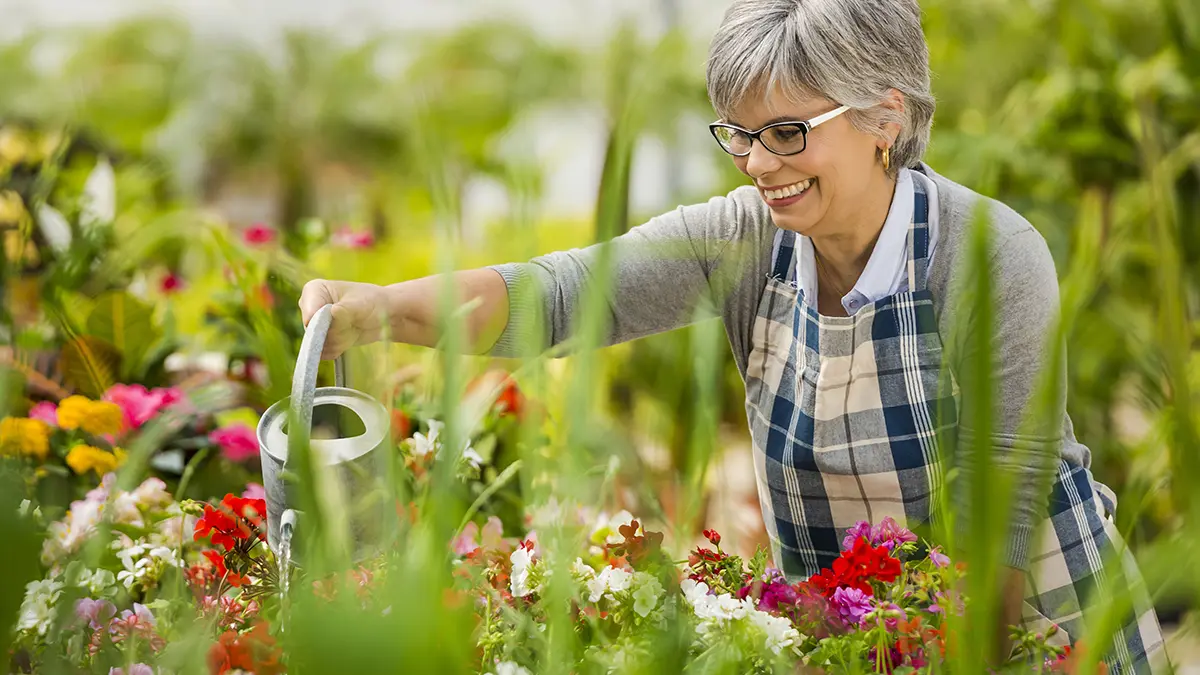 Photo of woman watering plants at a memory garden that help people with dementia.