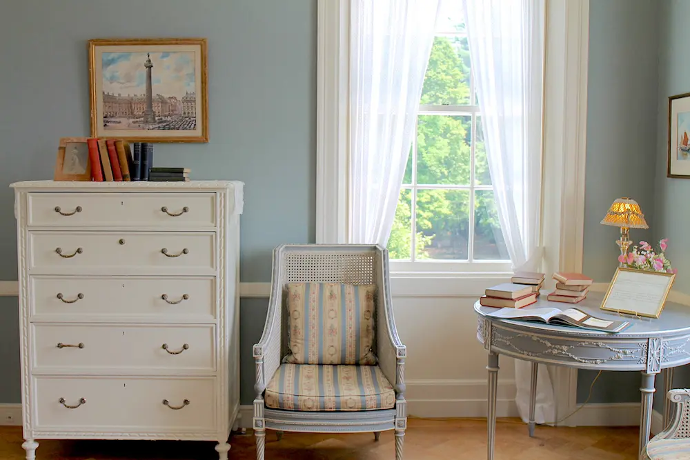 Picture of a seating area in a bedroom, which captures such cottagecore elements as books, flowers, and elegant yet functional pieces.